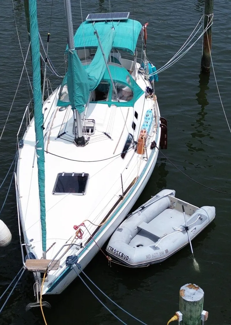 Slide: The Image of 1986 Scanmar 33 sailboat docked with dinghy, featuring teal canopy and clean white deck. - 3
