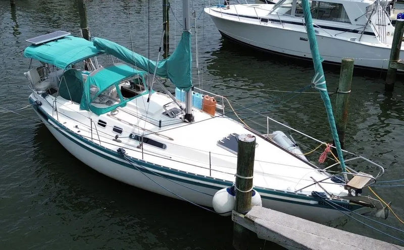 Slide: The Image of 1986 Scanmar 33 sailboat docked, featuring teal covers and a sleek white hull. - 7