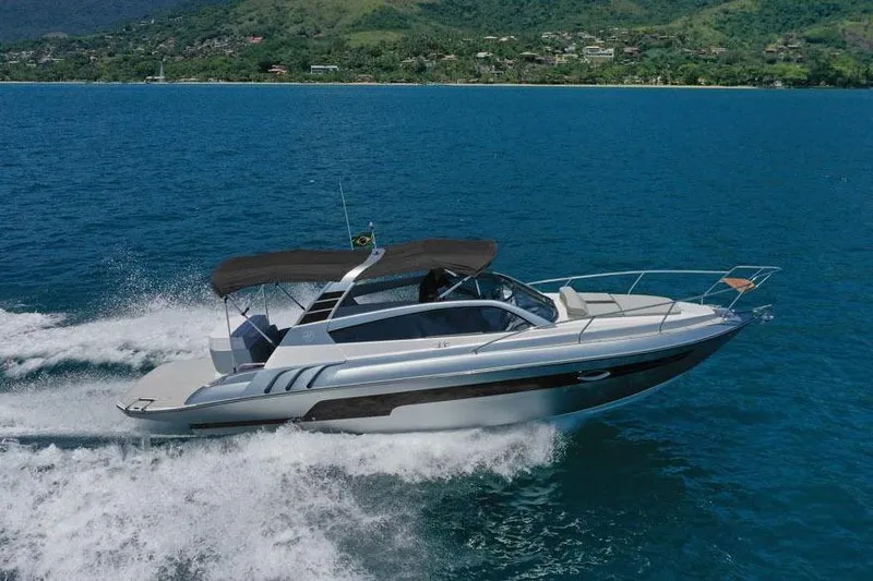 The Image of 2025 Hanover 305 Inboard boat cruising on blue ocean with scenic mountain backdrop. - 0