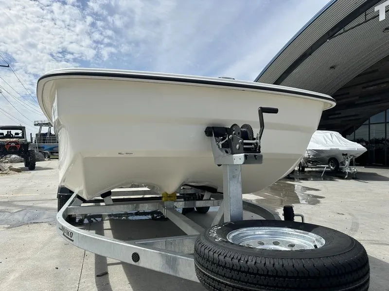 Slide: The Image of 2024 Mako Pro Skiff 19 CC on trailer, parked outdoors under a partly cloudy sky. - 6