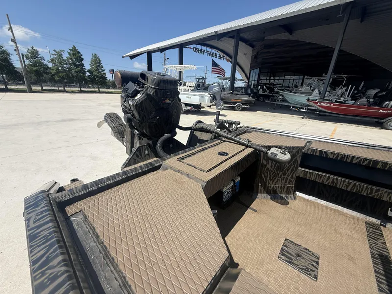 Slide: The Image of 2024 Prodigy 17x51 boat with camo interior, parked at a dealership under a clear sky. - 4