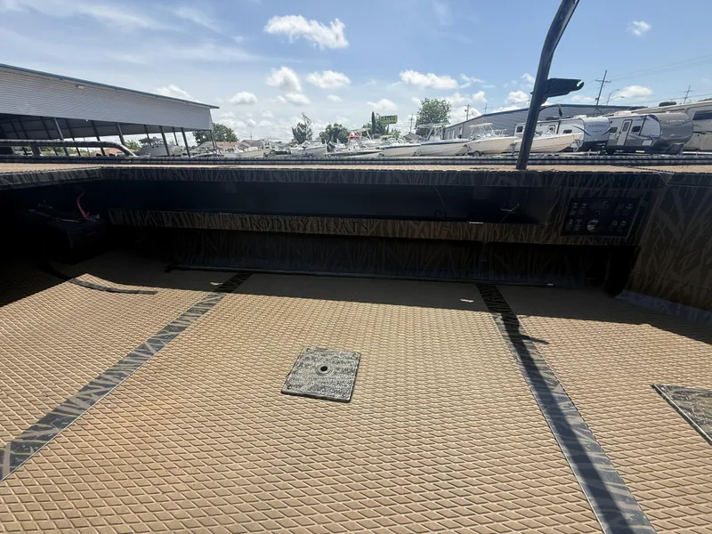Slide: The Image of 2024 Prodigy 17x51 boat interior with textured flooring and control panel, under a clear sky. - 9