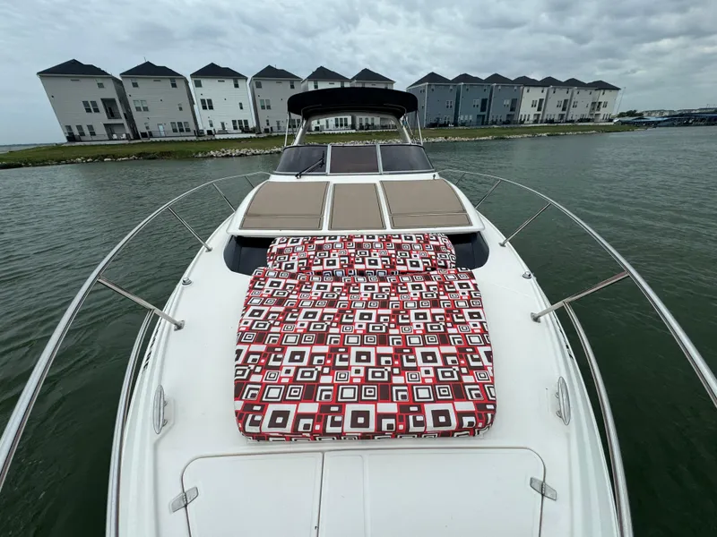 Slide: The Image of 2011 Regal 35 Express Cruiser with patterned sunbed, docked near modern townhouses. - 13