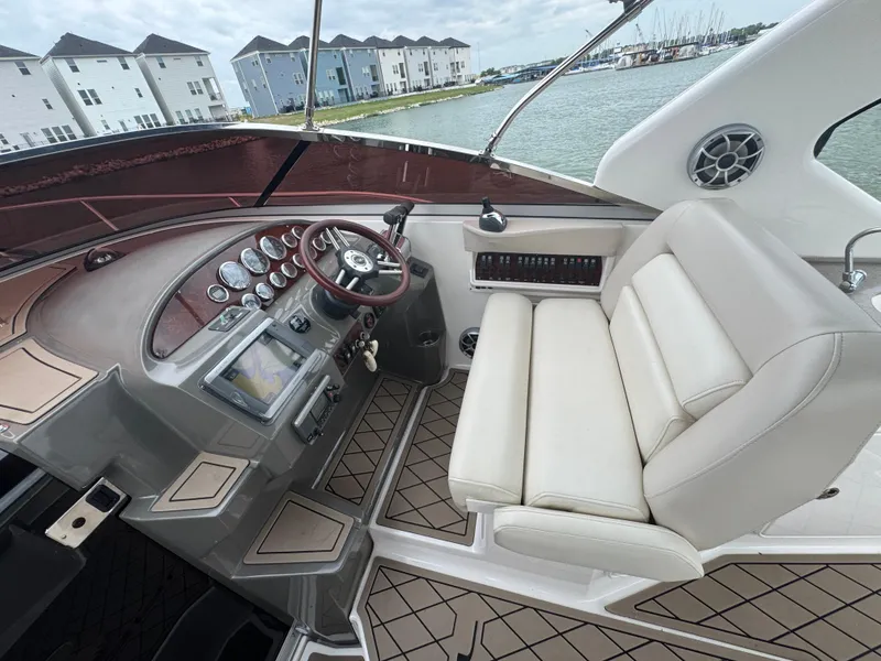 Slide: The Image of 2011 Regal 35 Express Cruiser cockpit with leather seating and control panel, docked by waterfront homes. - 17