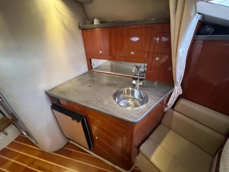 Slide: The Image of Compact kitchen area in a 2011 Regal 35 Express Cruiser with wood cabinetry and stainless steel sink. - 39