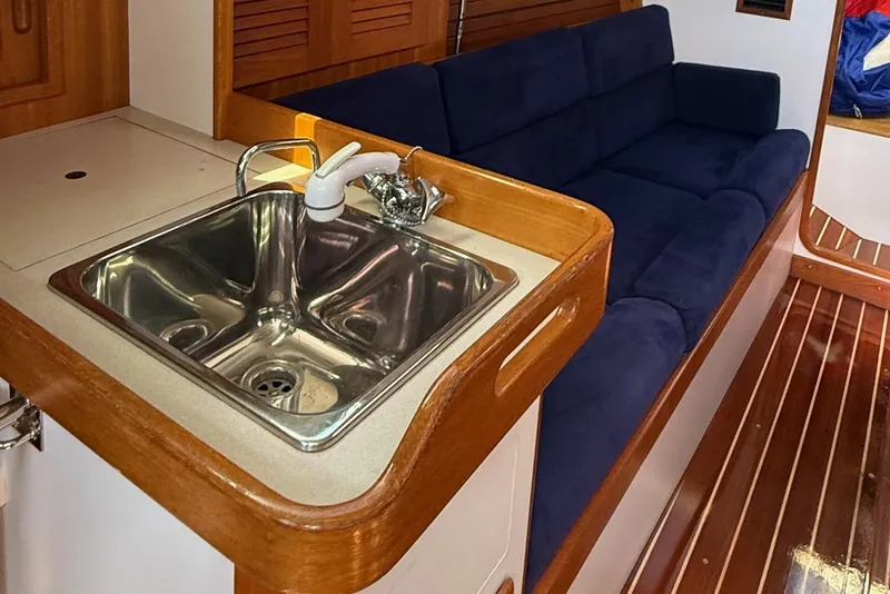 Slide: The Image of Interior of 2005 J Boats J/124, featuring a sink and blue cushioned seating. - 16