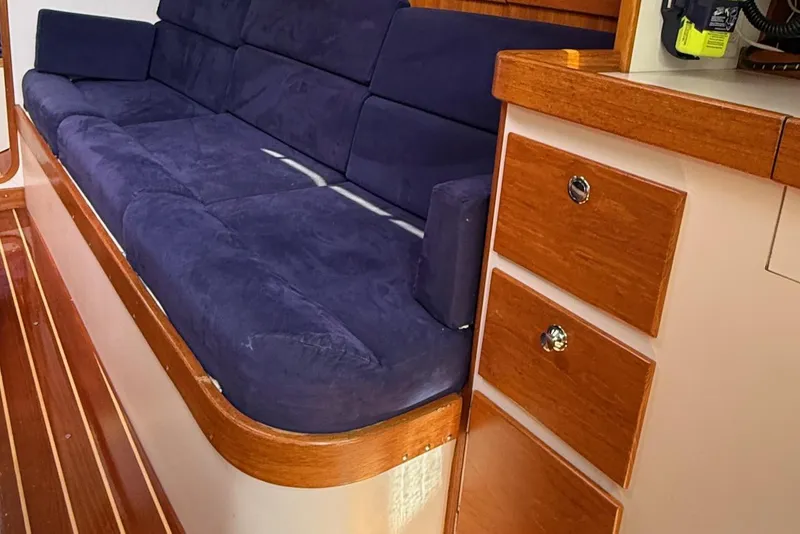 Slide: The Image of Interior of 2005 J Boats J/124, featuring a blue cushioned sofa and wooden cabinetry. - 18