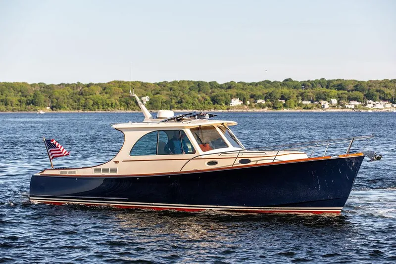 Slide: The Image of 2018 Hinckley Picnic Boat 37 MKIII cruising on a calm lake with scenic shoreline. - 10