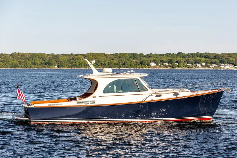 Slide: The Image of 2018 Hinckley Picnic Boat 37 MKIII cruising on a calm lake with scenic shoreline. - 12