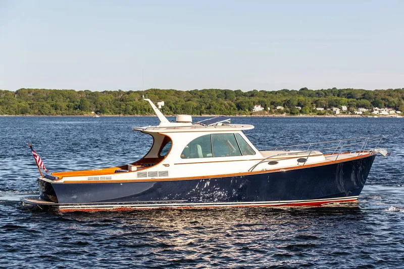 Slide: The Image of 2018 Hinckley Picnic Boat 37 MKIII cruising on a calm lake with scenic shoreline. - 13