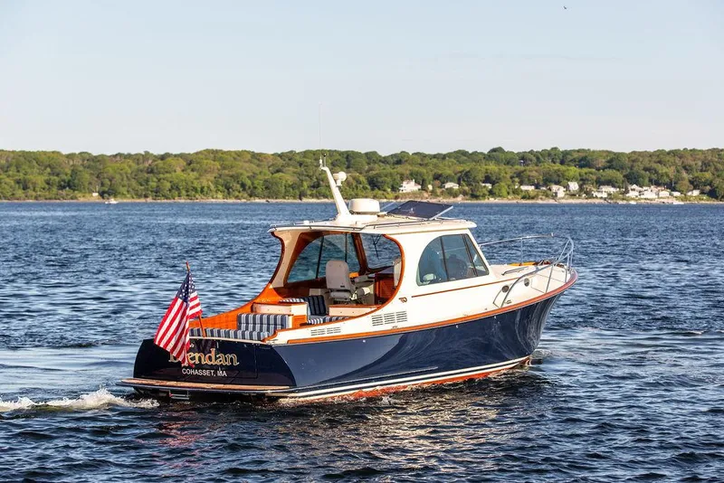 Slide: The Image of 2018 Hinckley Picnic Boat 37 MKIII cruising on a serene lake with American flag. - 16