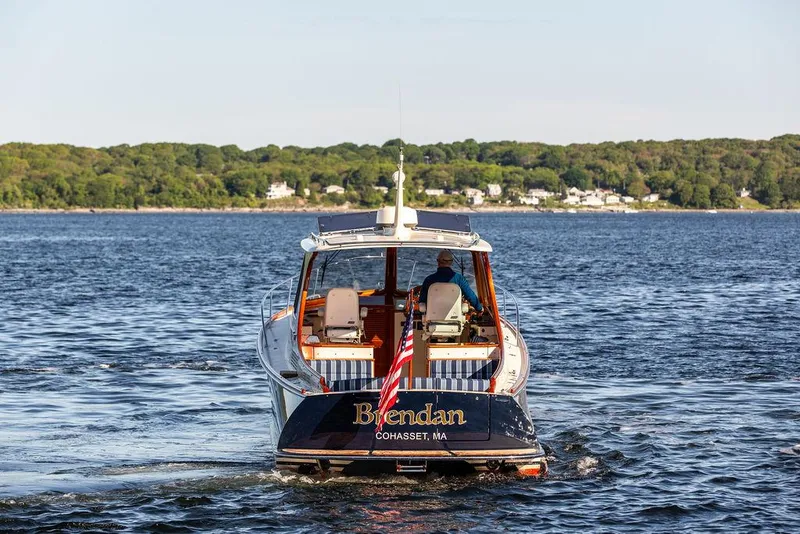Slide: The Image of 2018 Hinckley Picnic Boat 37 MKIII cruising on a scenic lake with lush green shoreline. - 18