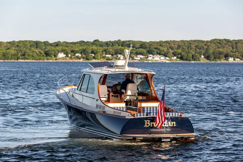 Slide: The Image of 2018 Hinckley Picnic Boat 37 MKIII cruising on a scenic lake with lush green shoreline. - 19