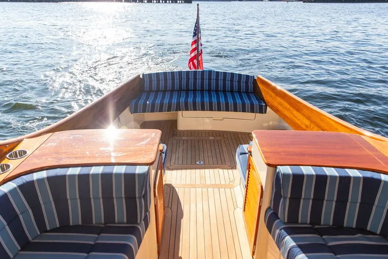 Slide: The Image of 2018 Hinckley Picnic Boat 37 MKIII with striped seating, wooden deck, and American flag on water. - 30