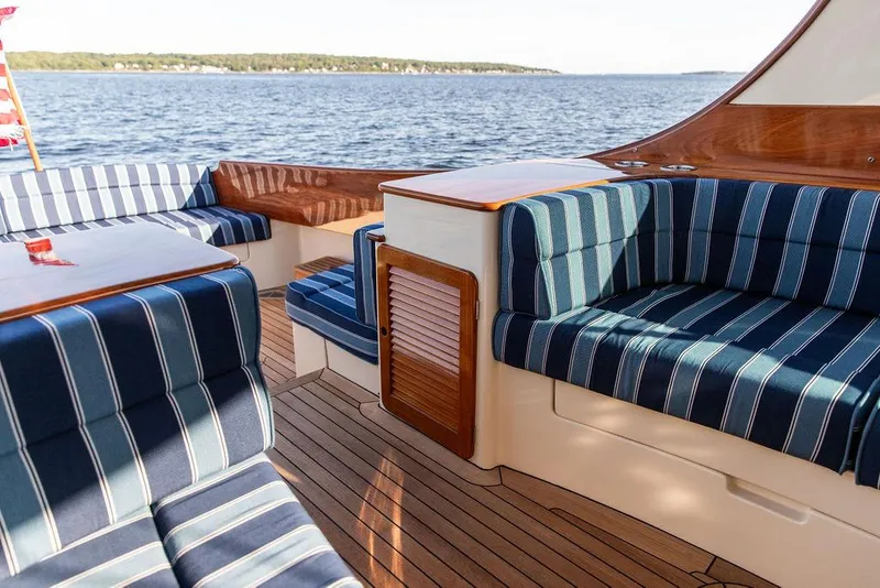 Slide: The Image of 2018 Hinckley Picnic Boat 37 MKIII with striped seating and wooden deck on a calm lake. - 33