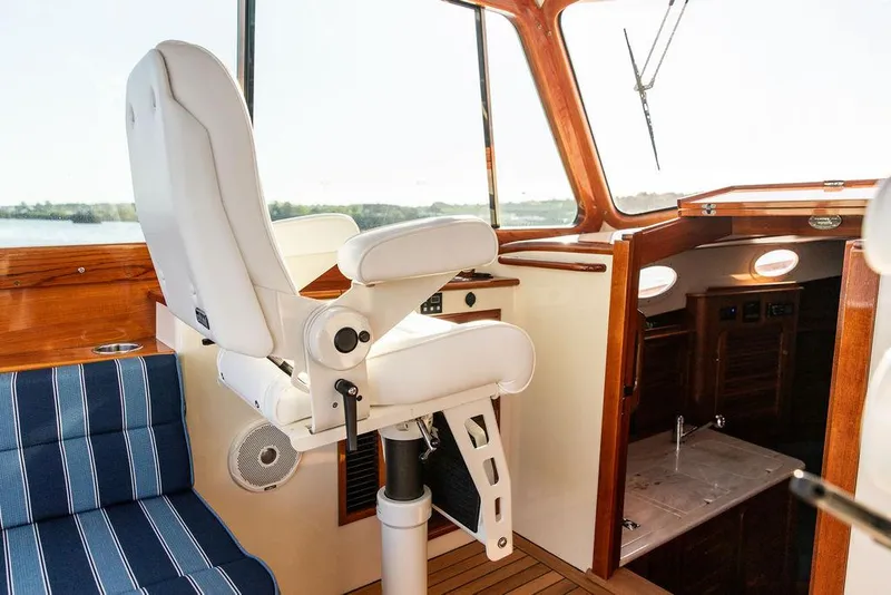 Slide: The Image of Helm station of 2018 Hinckley Picnic Boat 37 MKIII with white captain's chair and wooden interior. - 36