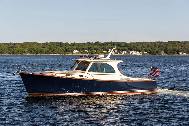 Slide: The Image of 2018 Hinckley Picnic Boat 37 MKIII cruising on a serene lake with lush green shoreline. - 5