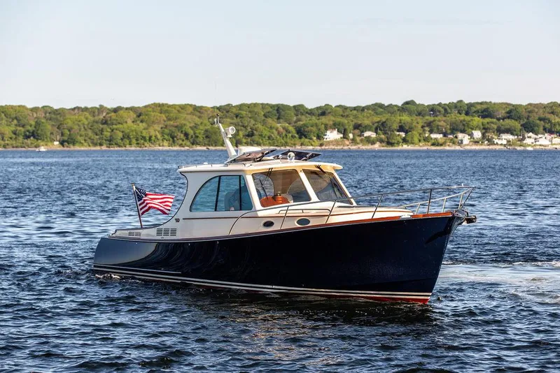 Slide: The Image of 2018 Hinckley Picnic Boat 37 MKIII cruising on a scenic lake with lush green shoreline. - 9