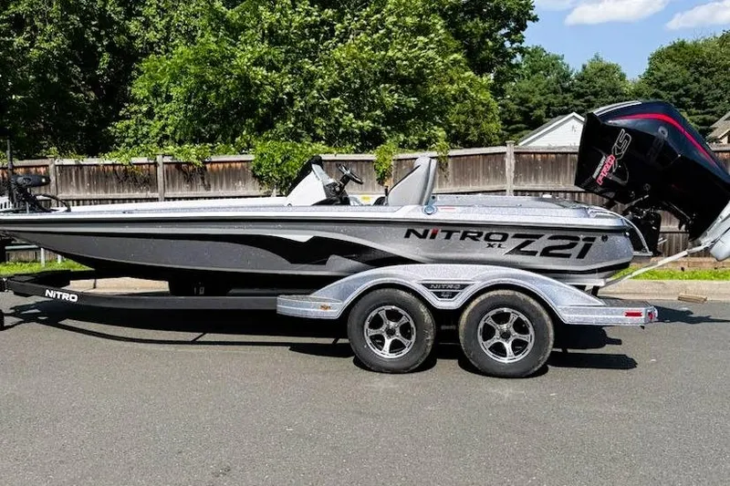 The Image of 2025 Nitro Z21 XL Pro boat on trailer, parked outdoors, with trees in background. - 0