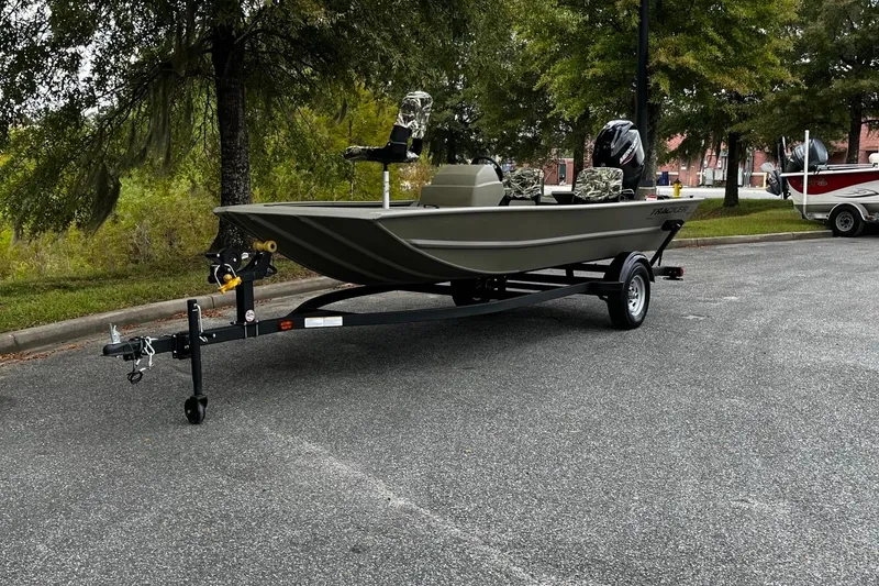 The Image of 2025 Tracker Grizzly 1754 SC boat on trailer, parked outdoors, surrounded by trees. - 12