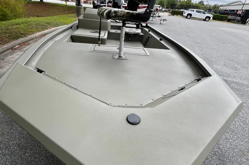 Slide: The Image of 2025 Tracker Grizzly 1754 SC boat, olive green, parked outdoors, featuring a camo seat. - 18