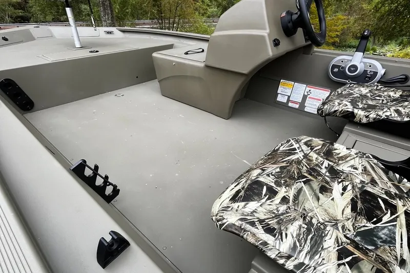 Slide: The Image of 2025 Tracker Grizzly 1754 SC boat interior with camo seats and steering console. - 19
