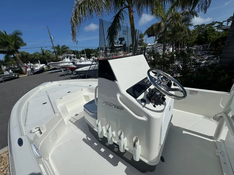 Slide: The Image of 2025 Skeeter SX 230 boat with sleek console and steering wheel, docked under palm trees. - 18