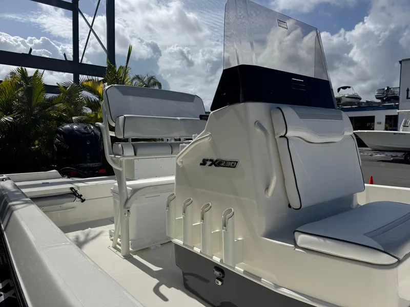 Slide: The Image of 2025 Skeeter SX 230 boat interior with seating and console, under a partly cloudy sky. - 8