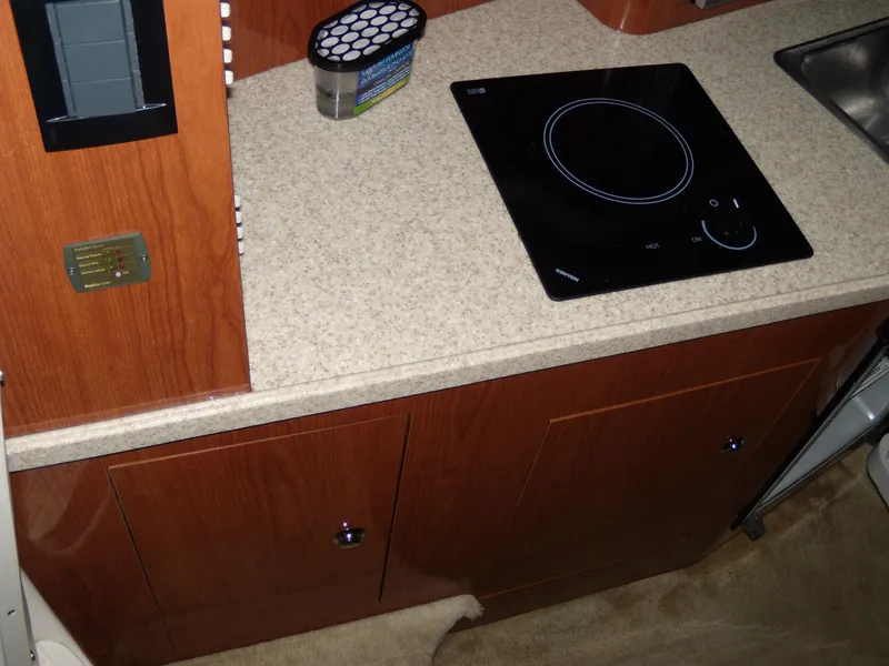 Slide: The Image of 2008 Regal Commodore 2665 galley with electric cooktop and wooden cabinetry. - 10