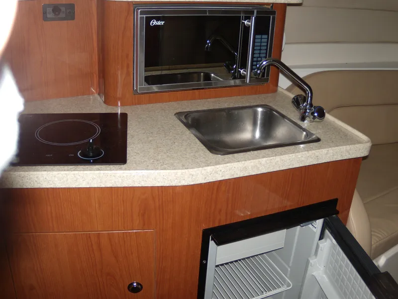 Slide: The Image of 2008 Regal Commodore 2665 boat kitchenette with sink, microwave, stove, and mini fridge. - 11