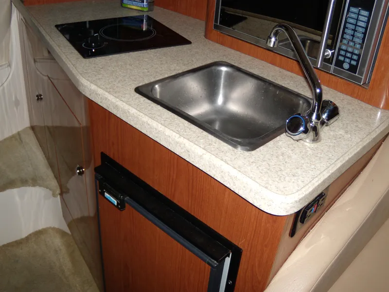 Slide: The Image of Compact kitchen area in a 2008 Regal Commodore 2665 boat, featuring a sink and stovetop. - 16