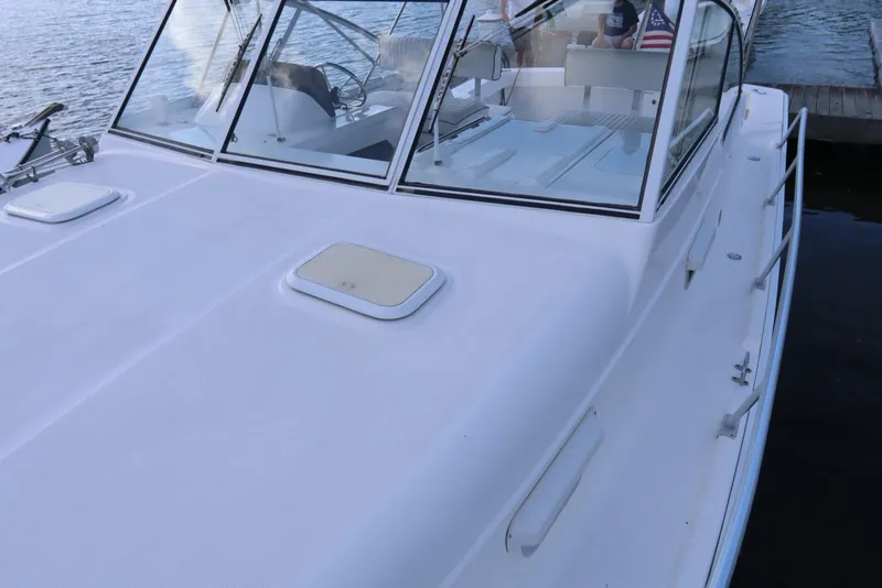 Slide: The Image of 2002 Mainship Pilot 34 boat with sleek white deck and windshield, docked by the water. - 13