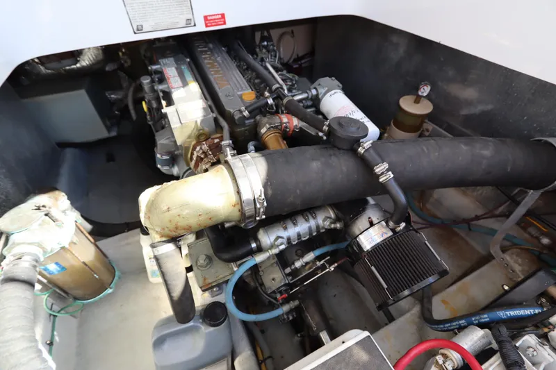Slide: The Image of Engine compartment of a 2002 Mainship Pilot 34 boat, showcasing mechanical components and hoses. - 33