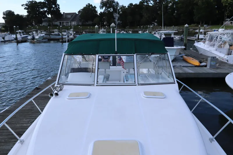 Slide: The Image of 2002 Mainship Pilot 34 docked at marina with green canopy and American flag. - 7