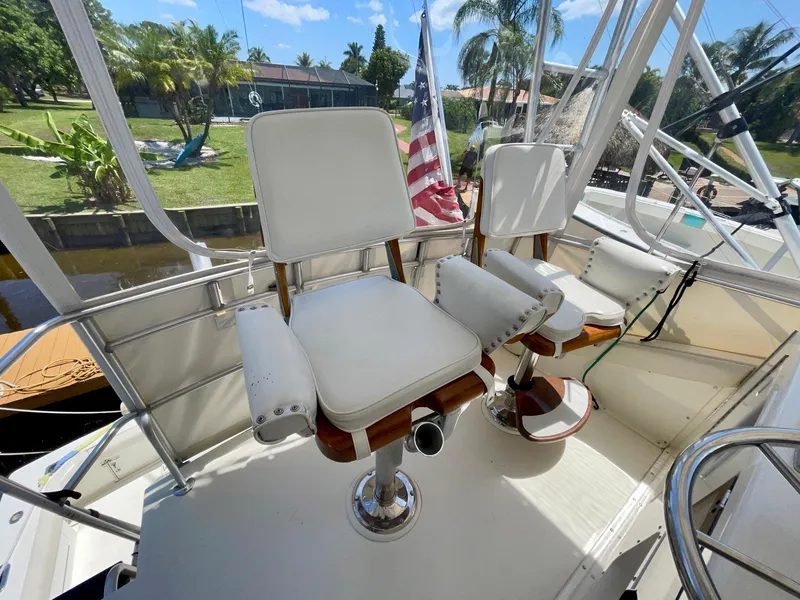 Slide: The Image of 1988 Bertram 43 Convertible boat helm with white captain chairs and American flag. - 10