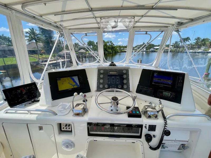 Slide: The Image of Helm of 1988 Bertram 43 Convertible yacht with navigation equipment and scenic waterway view. - 12