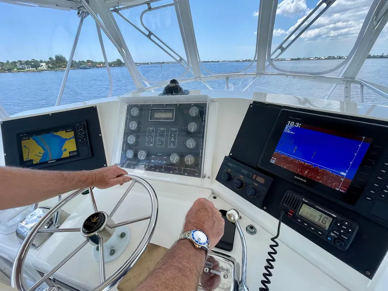 Slide: The Image of 1988 Bertram 43 Convertible helm with navigation screens and steering wheel on open water. - 13