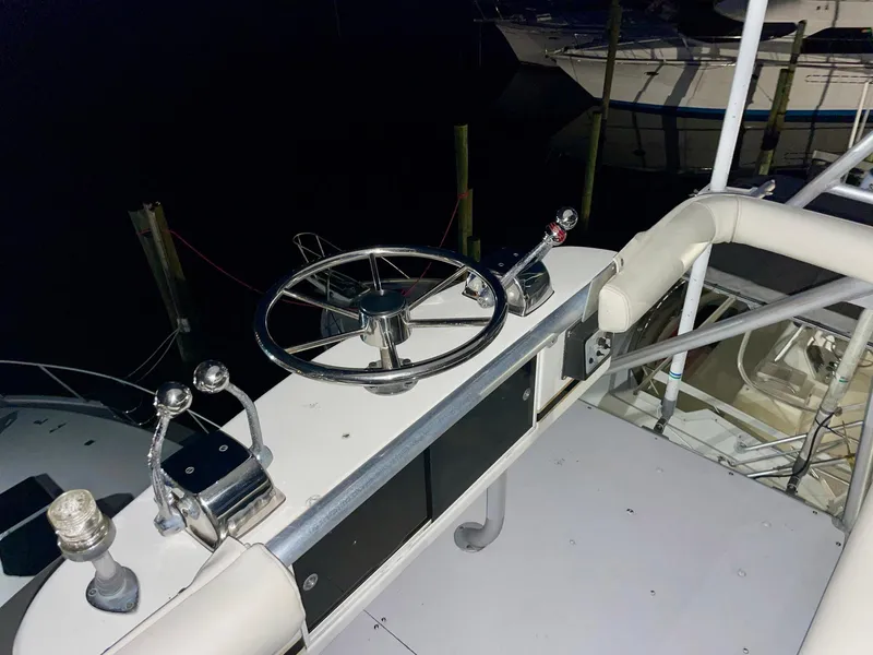 Slide: The Image of 1988 Bertram 43 Convertible yacht helm with steering wheel and controls at night. - 20