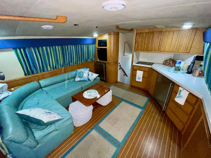 Slide: The Image of 1988 Bertram 43 Convertible interior with teal seating, striped curtains, and wooden cabinetry. - 21