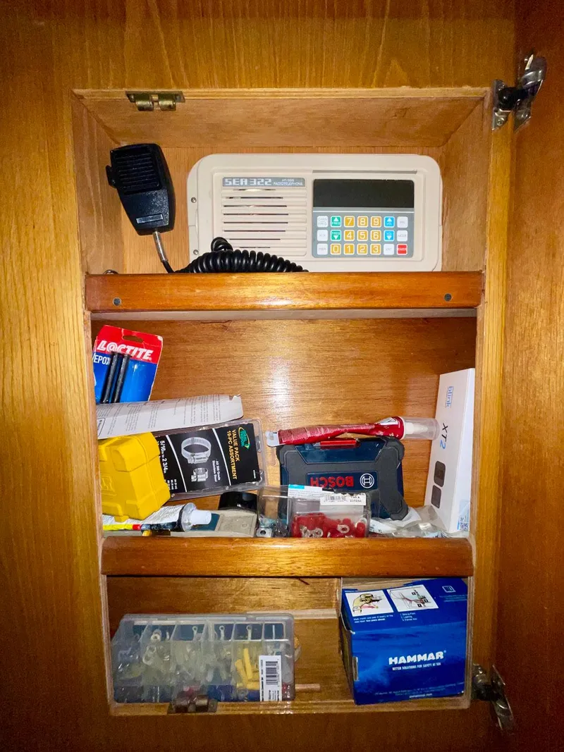 Slide: The Image of Wooden cabinet with marine radio and assorted supplies on a 1988 Bertram 43 Convertible. - 24
