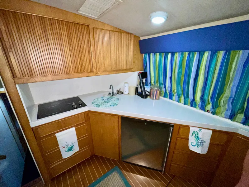 Slide: The Image of 1988 Bertram 43 Convertible kitchen with wood cabinets, striped curtains, and modern appliances. - 26