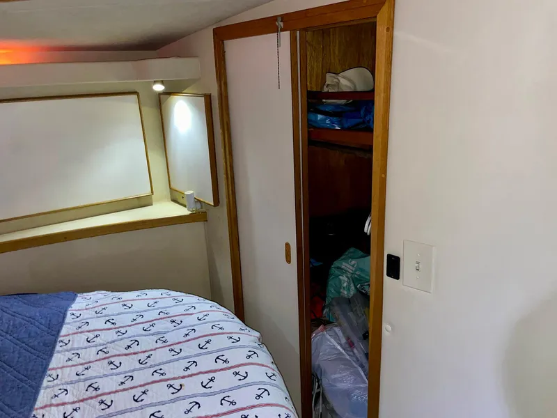 Slide: The Image of 1988 Bertram 43 Convertible cabin interior with bed, closet, and nautical-themed bedding. - 32