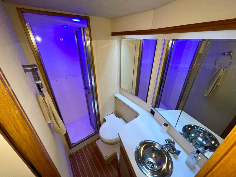 Slide: The Image of Luxurious bathroom in a 1988 Bertram 43 Convertible yacht with modern fixtures and blue lighting. - 33