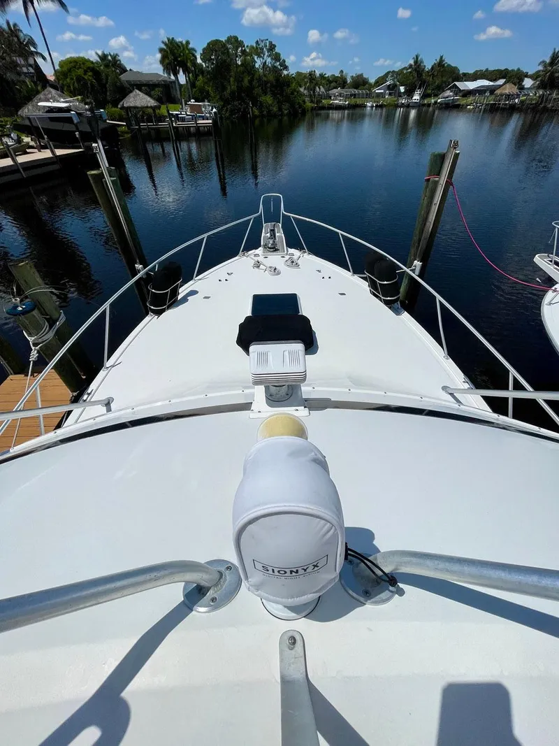 Slide: The Image of 1988 Bertram 43 Convertible yacht bow view at a serene marina. - 4