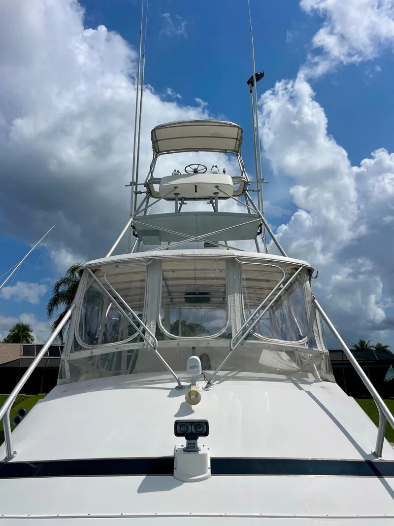 Slide: The Image of 1988 Bertram 43 Convertible yacht under a bright blue sky with clouds. - 6