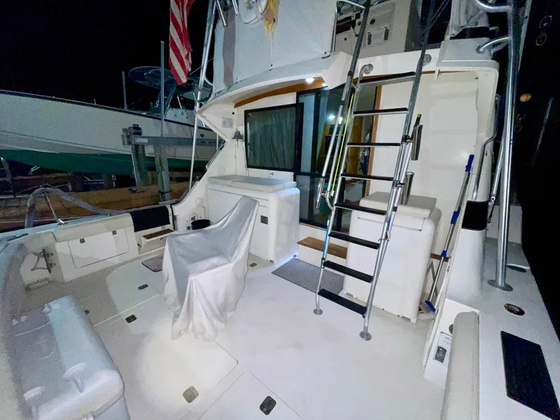 Slide: The Image of 1988 Bertram 43 Convertible yacht deck with seating, ladder, and American flag at night. - 8