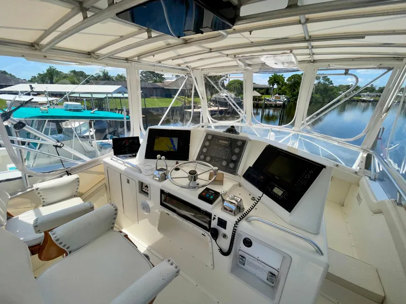 Slide: The Image of 1988 Bertram 43 Convertible yacht helm with modern navigation equipment and scenic marina view. - 9