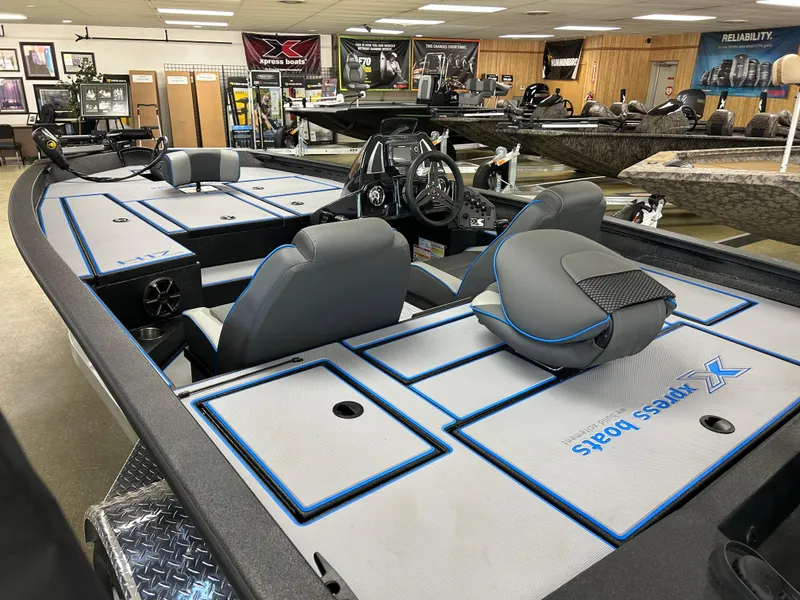 Slide: The Image of 2025 Xpress H17 boat interior with gray seating and blue accents in showroom. - 2
