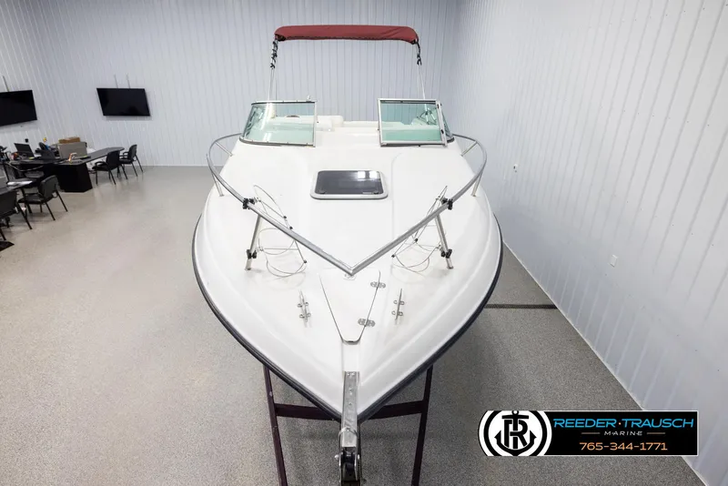 Slide: The Image of 1999 Crownline 242 CR boat in showroom, featuring sleek design and red canopy. - 17