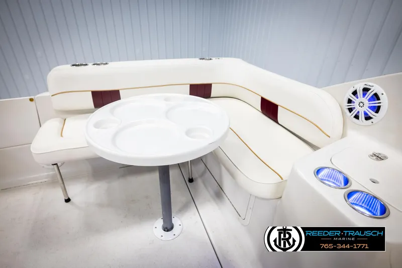 Slide: The Image of 1999 Crownline 242 CR boat interior with white seating, round table, and blue-lit speakers. - 23